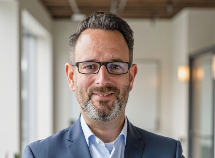Mann mit Brille, hellem Hemd und dunklem Sakko